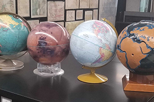 Four globes on top of a black cabinet.