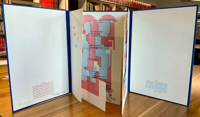 An artist book propped up on a wooden table